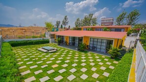 Un edificio moderno con tejado rojo y ventanas grandes, rodeado de un césped cuidado con losetas de piedra.