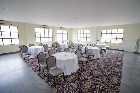 A conference room with multiple tables and chairs, large windows, and a patterned carpet.