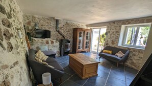 Un salon rustique avec des murs en pierre, une cheminée, un canapé, une table basse en bois et un téléviseur.