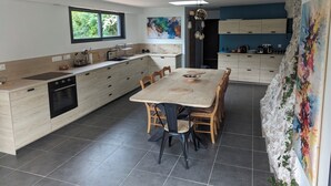 Une cuisine moderne dotée d’un îlot central, d’une table à manger et d’une grande fenêtre.