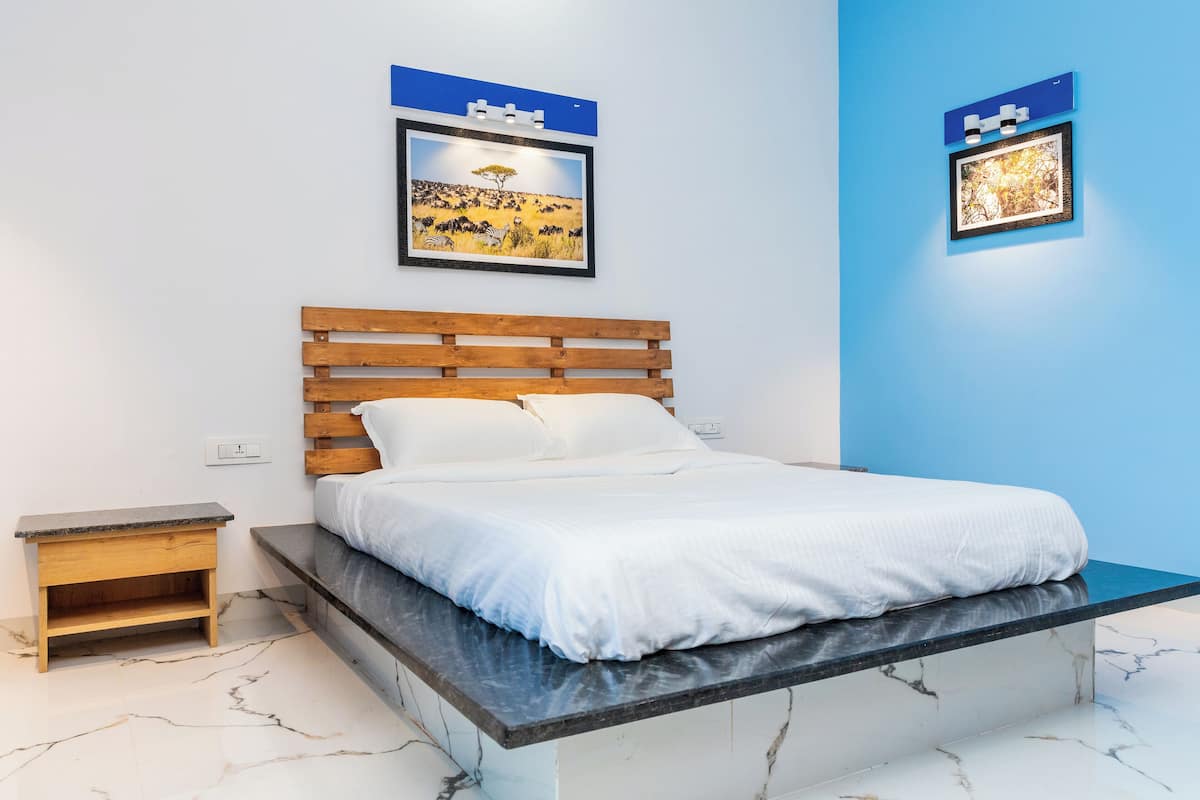 Une chambre à coucher avec un lit en bois, une table de chevet, un sol en marbre et deux tableaux encadrés accrochés au mur.