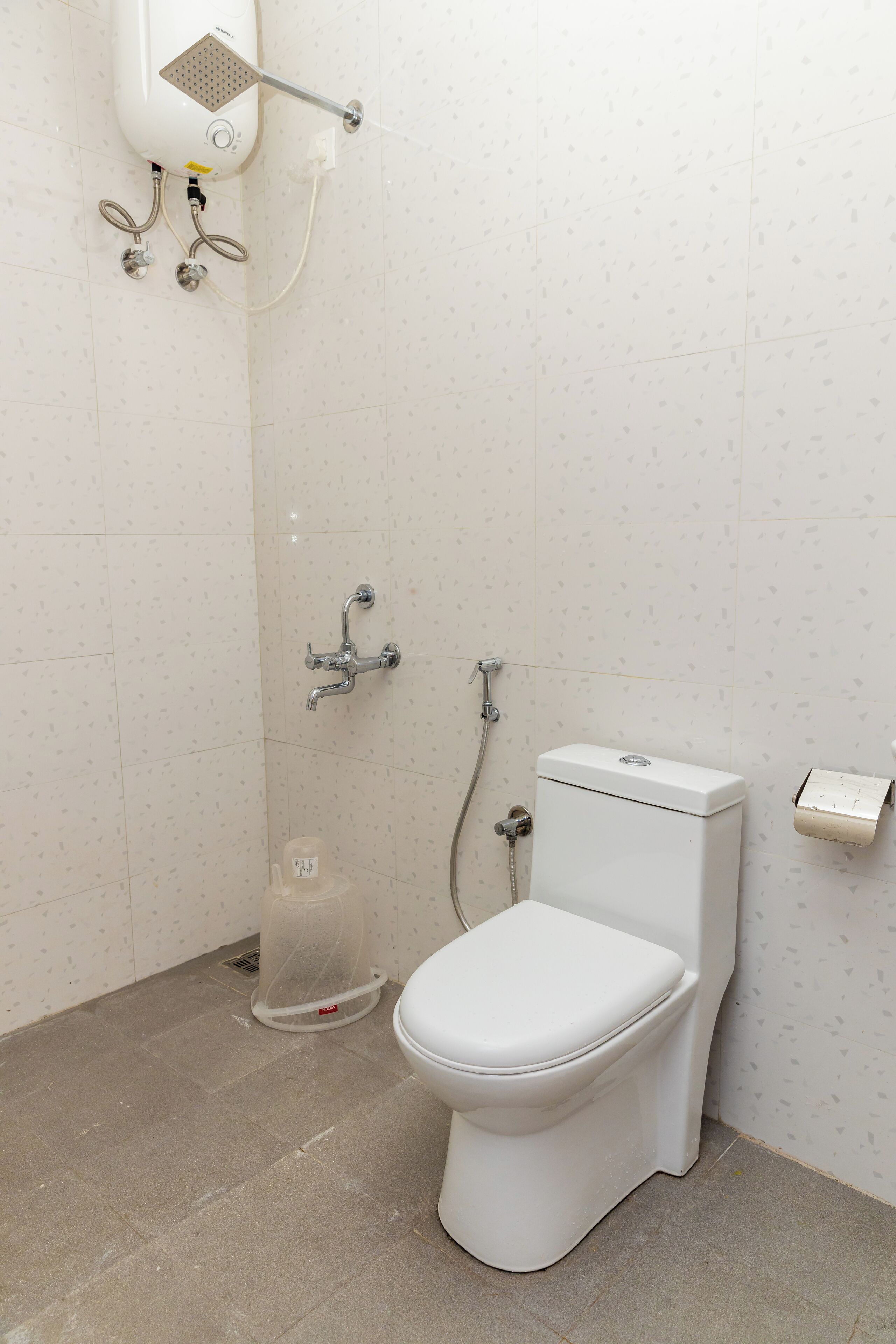 A bathroom with a toilet, shower, and hand dryer.