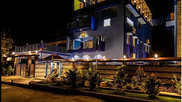 A multi-story building with a modern design, featuring balconies and a well-lit entrance area. - Panism Lifestyle (Vanur)