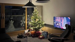 A living room with a Christmas tree, a television, and a large window with a view of a snowy scene outside. - Seaside paradise (Palanga)