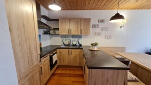 Una cocina moderna con armarios de madera, una isla central, iluminación colgante y una pequeña planta en maceta.