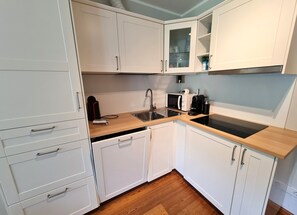 A compact kitchen with white cabinets, a wooden countertop, a sink, a microwave, and a coffee maker. - Alpenrose Boutique Top 6 by Globalimmoservice (Bad Kleinkirchheim)