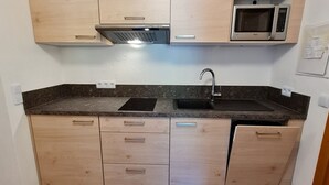 Una cocina con gabinetes de madera, un microondas, un fregadero y una campana extractora de acero inoxidable.