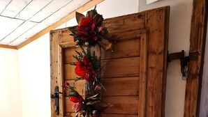 A wooden door with a decorative wreath, a bench with floral cushions, and a wooden floor. - Die Alte Scheune by Globalimmoservice (Bad Kleinkirchheim)