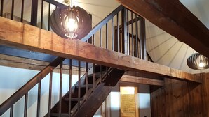 A wooden staircase with metal railings and a hanging light fixture. - Die Alte Scheune by Globalimmoservice (Bad Kleinkirchheim)