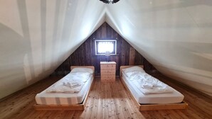 A small, cozy attic bedroom with two single beds, wooden flooring, a small dresser, and a window providing natural light. - Die Alte Scheune by Globalimmoservice (Bad Kleinkirchheim)