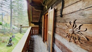 Una baita di legno con un balcone affacciato su una zona boschiva.
