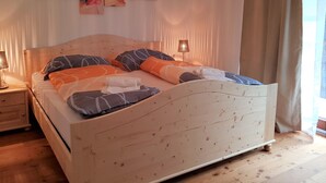 Ein hölzernes Bett mit Kopfteil, zwei Nachttische und ein an der Wand befestigtes Kunstwerk.