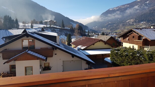 Ein Bergdorf mit traditionellen Holzhäusern, blauem Himmel und schneebedeckten Hügeln.
