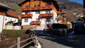 Ein mehrstöckiges Gebäude mit geneigtem Dach, hölzernen Balkonen und Blick auf eine verschneite Landschaft.
