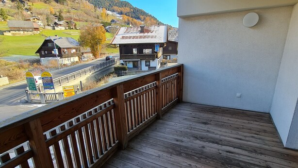 A wooden deck with a view of a village and mountains.
