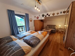 A bedroom with a bed, a sofa, a small table, and a mirror.
