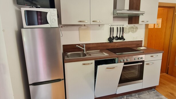Angolo cottura attrezzato con frigorifero, microonde, piano cottura, forno e lavello.