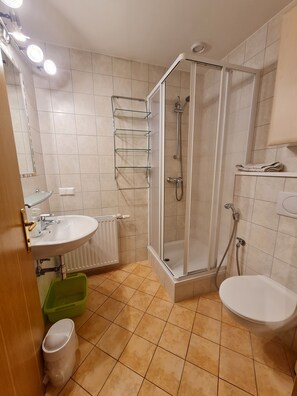 A bathroom with a shower, sink, toilet, and a glass shower door.
