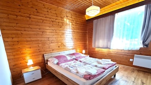 Un dormitorio con paneles de madera, una cama, lámparas de noche y una ventana con cortinas.