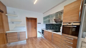 Eine moderne Küche mit Holzausstattung, einer Edelstahlspüle und einem Einbauofen.