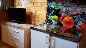A compact kitchen with wooden walls, a white countertop, and a built-in stove. - Der Kristall Top 3 by Globalimmoservice (Bad Kleinkirchheim)