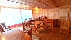 A wooden interior with a dining table, chairs, and a bench.