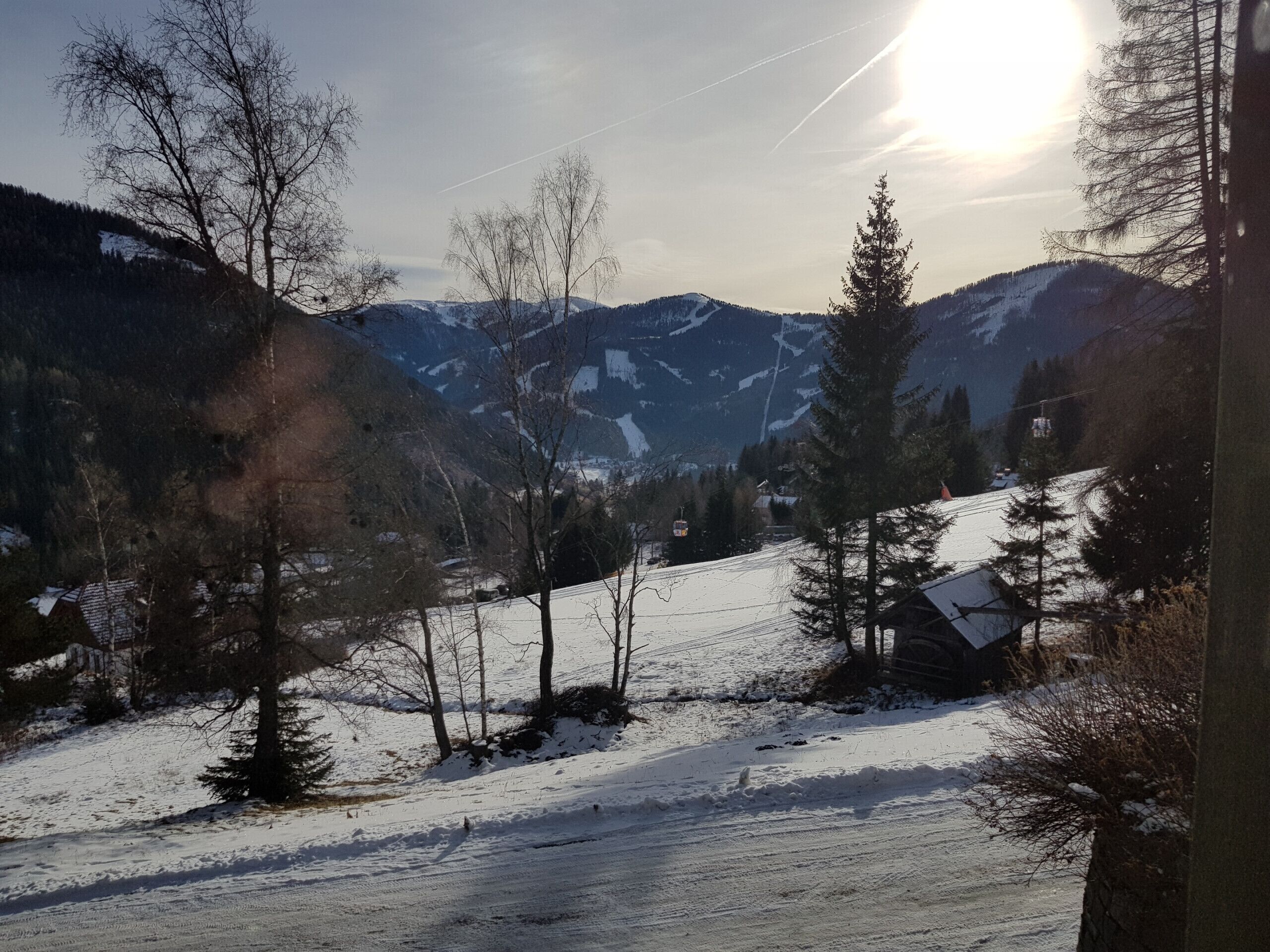 A snowy mountain landscape with a clear sky, a ski lift, and a cabin.