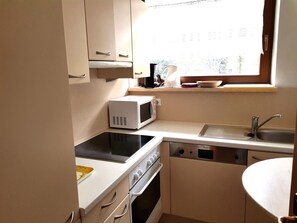 A compact kitchen with a microwave, stove, sink, and oven.