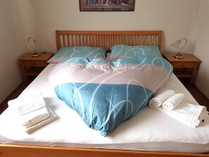 A neatly made bed with a patterned bedspread, two pillows, and two bedside tables with lamps.