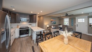 A modern kitchen with a dining area, wooden flooring, and a view of the beach. - 3BR - Walk to Beach + Boardwalk | Near Downtown OC (Ocean City)