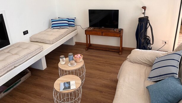 A compact living space with a sofa, a bed, a TV, and a small table with decorative items. - 1 Bedroom Apartment in Cernobbio (Cernobbio)