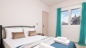 A double bed with white and blue bedding, two pillows, and a folded white towel on the side.