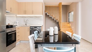 A modern kitchen with a central island, built-in appliances, and a staircase leading to an upper level.