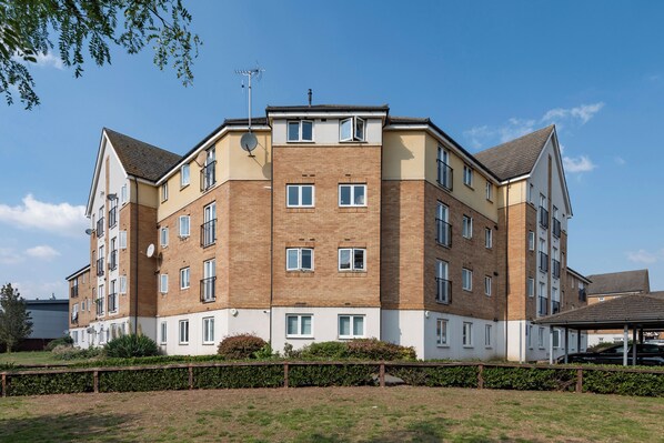 A multi-story residential building with a brick facade, multiple windows, and a flat roof. - Stylish Elegant New Flat 5 Min from Crossrail (London)
