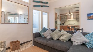 A modern living room with a grey sofa, a large mirror, and a kitchen visible through an open door. - Italianway - Vele D'Amare (Imperia)