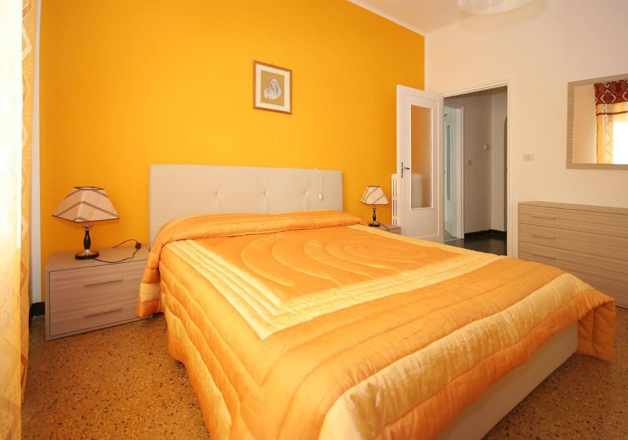 Une chambre à coucher avec un lit, deux tables de chevet, une commode, une porte et un miroir.