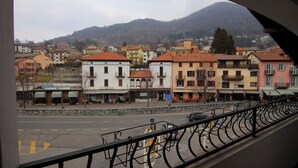 A street view with buildings, a road, and a mountain in the background. - Italianway - Piazza Nuova 3 (Centro Valle Intelvi)