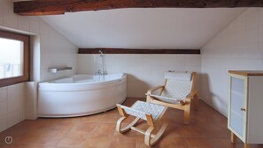 Een badkamer met een bad, een houten schommelstoel en een kast.