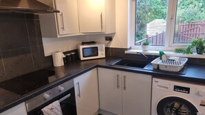 A compact kitchen with a microwave, sink, and built-in washing machine. - Lovely 2-bed House in Sunderland (Sunderland)