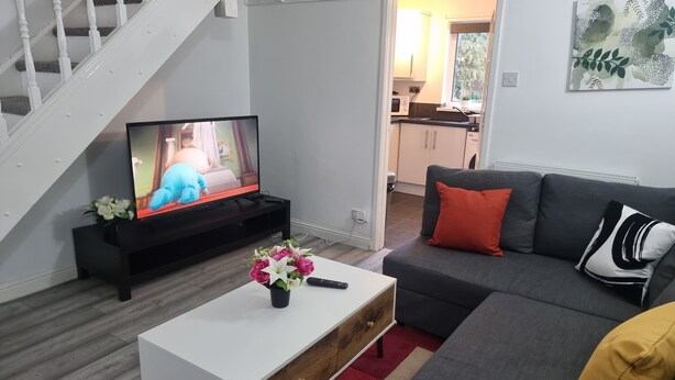 A living room with a television, sofa, coffee table, and staircase. - Lovely 2-bed House in Sunderland (Sunderland)