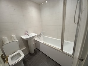 A modern bathroom with a toilet, sink, and bathtub.