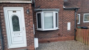 A brick house with a white door, a small window, and a gravel driveway. - Lovely 2-bed House in Sunderland (Sunderland)