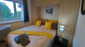 A bedroom with a bed, a window, a bedside table, and a wall-mounted lamp. - Lovely 2-bed House in Sunderland (Sunderland)