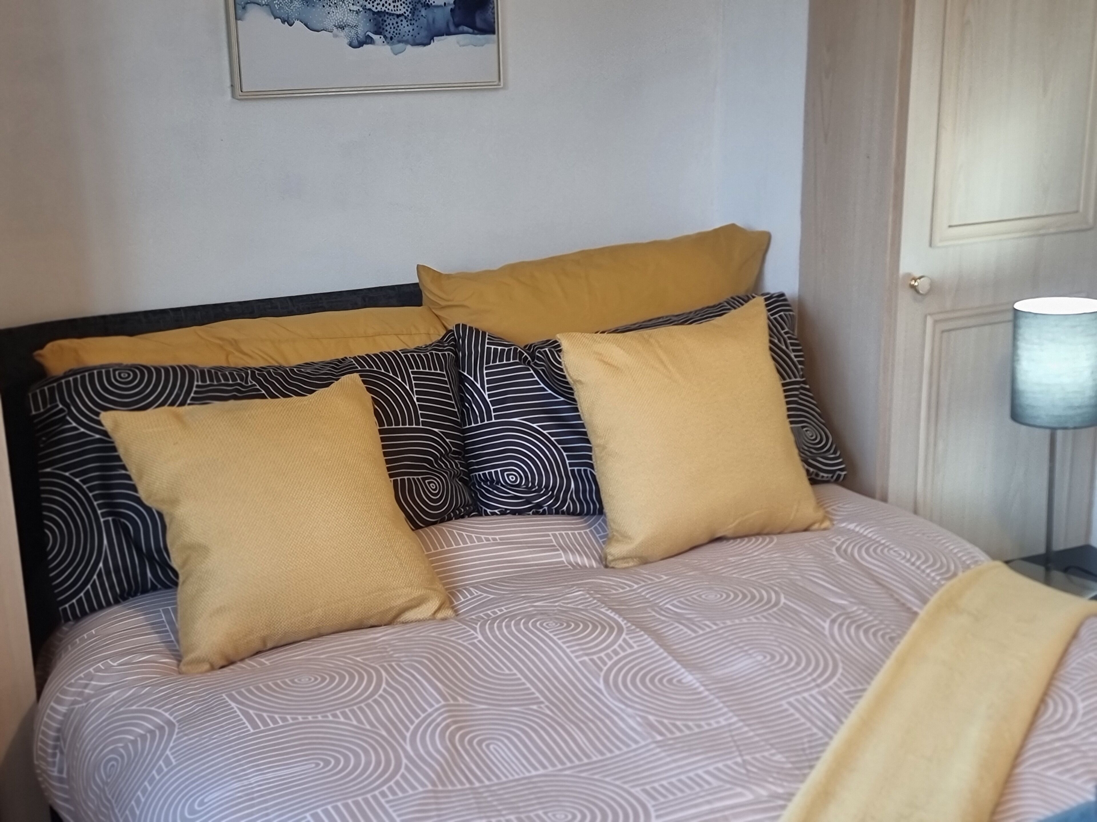 Ein Bett mit gemusterten Betttextilien und mehreren Kissen.