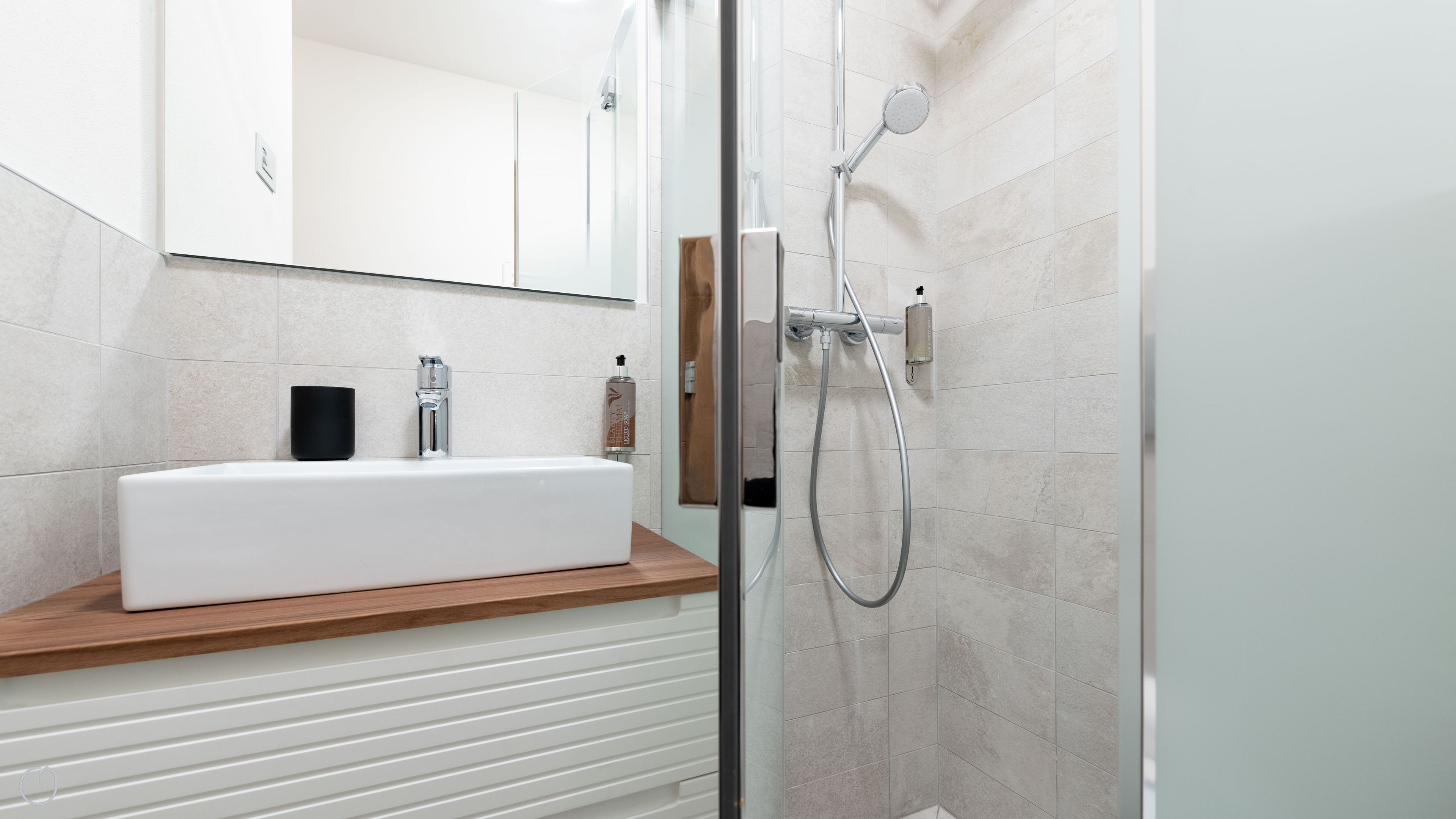 Une salle de bain moderne avec un lavabo blanc, un miroir et une douche à parois de verre.