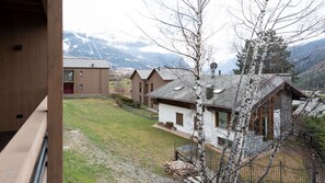 Vista de una zona residencial con casas de madera, un jardín césped y montañas al fondo.