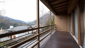 Un balcón con baranda de madera que da a un paisaje montañoso.