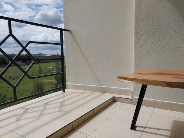A balcony with a tiled floor, a wooden table, and a metal railing.