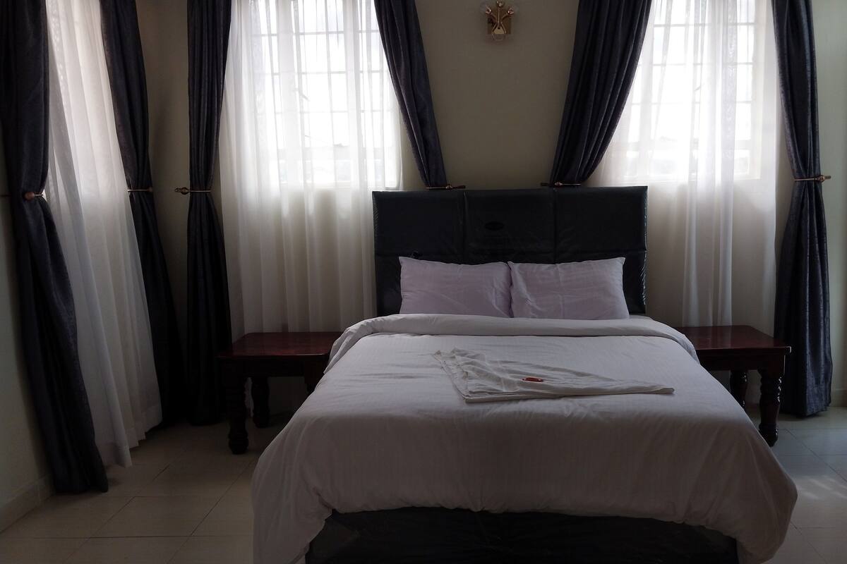 A neatly made bed with white linens, two bedside tables, and a headboard.