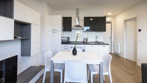 Una cocina moderna con armarios blancos, horno integrado y campana extractora de acero inoxidable.